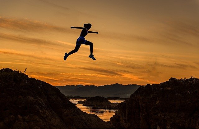 山を飛ぶように駆ける女性のシルエットの写真